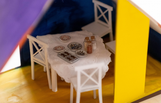 Ein Esstisch in einem Puppenhaus ist gedeckt.