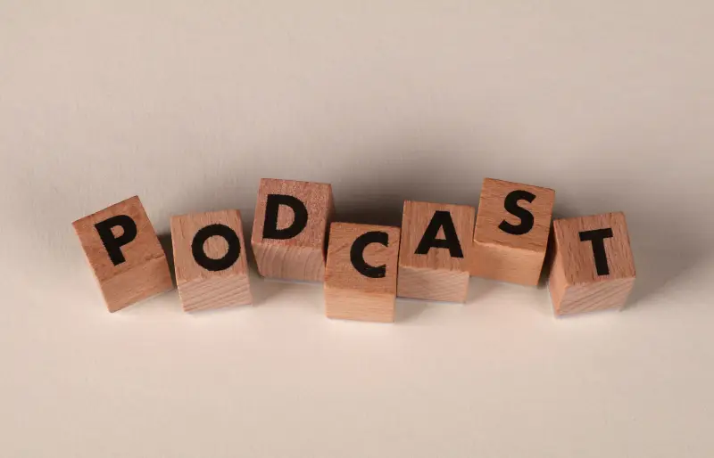 Holzwürfel, die nebeneinander liegen und das Wort "Podcast" bilden