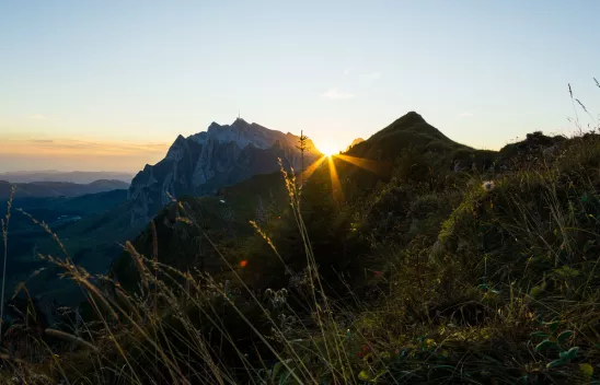 Die Sonne geht zwischen zwei Gipfeln am Horizont auf.
