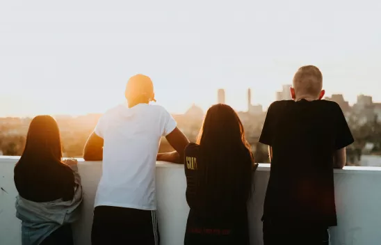 Vier Jugendliche blicken auf die Skyline einer Stadt.
