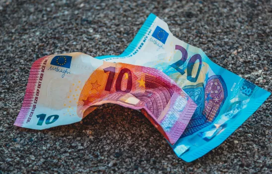 Ein Zehn-Euro-Schein und ein Zwanzig-Euro-Schein liegen zweknittert auf dem Asphalt. Ein Zehn-Euro-Schein und ein Zwanzig-Euro-Schein liegen zweknittert auf dem Asphalt.