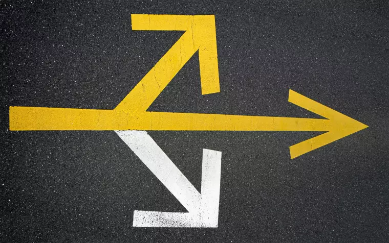 Drei Pfeile auf dem Asphalt weisen in unterschiedliche Richtungen.