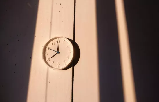 Eine weiße, analoge Wanduhr im Licht der Sonne. Eine weiße, analoge Wanduhr im Licht der Sonne.
