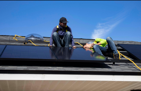 Zwei Personen arbeiten auf einem Dach an einem Solarpanel