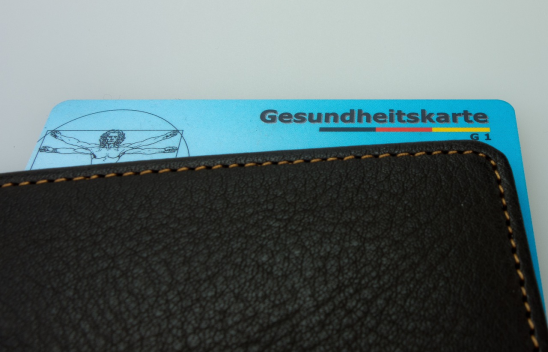 Eine blaue Gesundheitskarte ragt aus einem Portemonnaie heraus