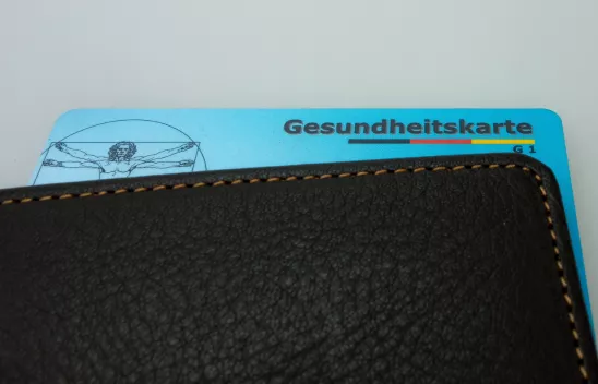 Eine blaue Gesundheitskarte ragt aus einem Portemonnaie heraus