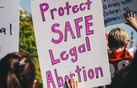 Eine Person hält ein Schild auf einer Demonstration mit der Aufschrift: "Protect safe legal abortion", zu Deutsch "Schützt sicheren und legalen Schwangerschaftsabbruch" Eine Person hält ein Schild auf einer Demonstration mit der Aufschrift: "Protect safe legal abortion", zu Deutsch "Schützt sicheren und legalen Schwangerschaftsabbruch"
