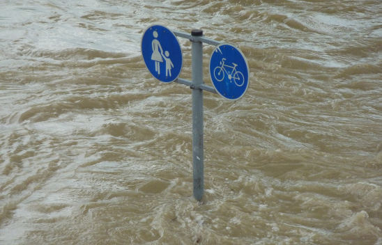Wassermassen, die ein Verkehrsschild überfluten, das einen Fußgänger- und einen Radweg anzeigt