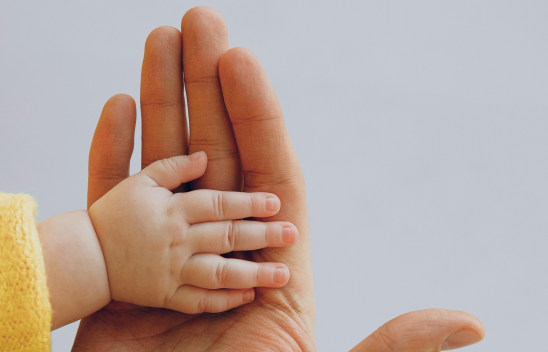 Eine Kinderhand liegt auf einer Erwachsenenhand