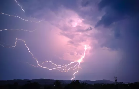 Foto eines bewölkten Himmels, der in verschiedenen lila-Tönen gefärbt ist. Im Zentrum des Bildes ist ein Blitz zu sehen. Foto eines bewölkten Himmels, der in verschiedenen lila-Tönen gefärbt ist. Im Zentrum des Bildes ist ein Blitz zu sehen.