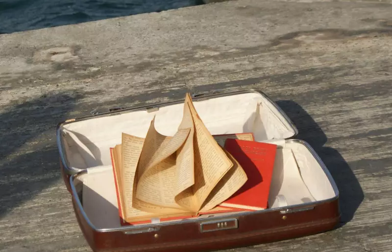 Offener Koffer mit zwei Büchern, von denen eines aufgeschlagen ist.