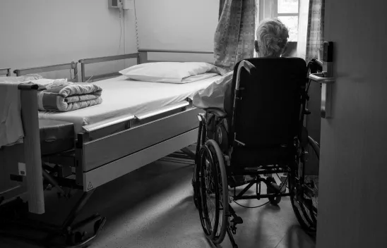 Pflegebedürftige Person im Rollstuhl vor Pflegebett. Pflegebedürftige Person im Rollstuhl vor Pflegebett.