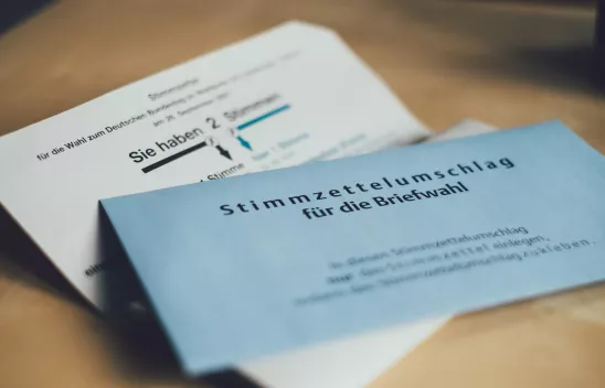 Ein aufgeklappter Stimmzettelbrief, auf dem ein blauer Stimmzettelumschlag für die Briefwahl liegt. Ein aufgeklappter Stimmzettelbrief, auf dem ein blauer Stimmzettelumschlag für die Briefwahl liegt.