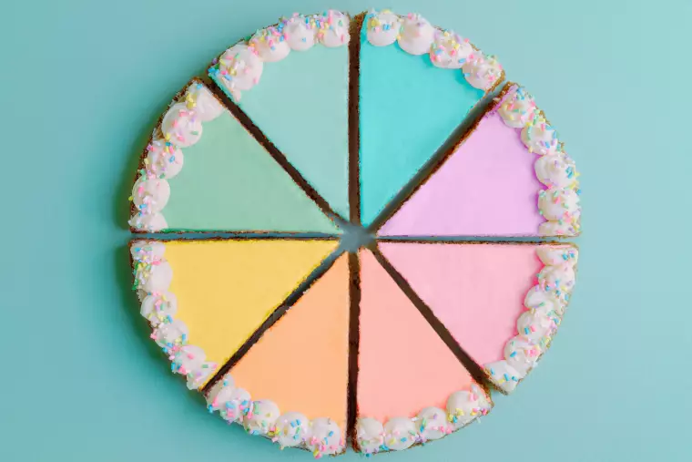 Ein Kuchen ist aufgeschnitten in Kuchenstücke in unterschiedlichen Farben.