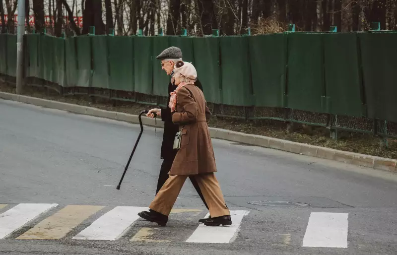 Zwei ältere Personen überqueren eine Straße