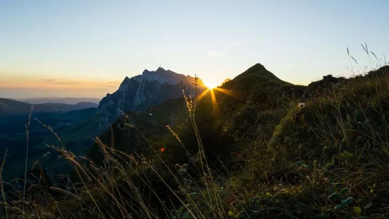Die Sonne geht zwischen zwei Gipfeln am Horizont auf.