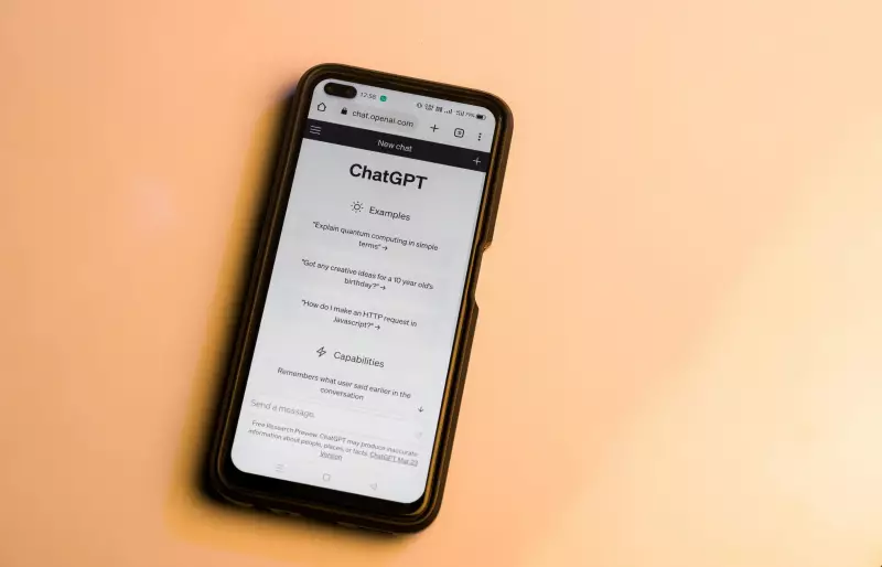 Ein Handy vor einem orangefarbenen Hintergrund, auf dem Handy ist ChatGPT geöffnet