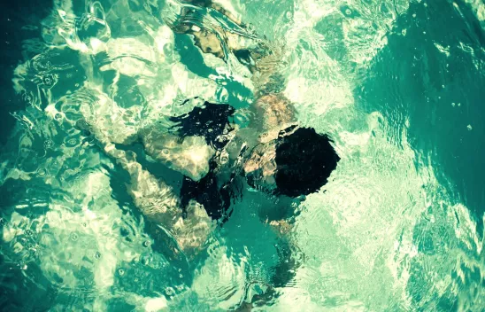Ein Mensch taucht in einem Swimming Pool, aus der Vogelperspektive betrachtet. Ein Mensch taucht in einem Swimming Pool, aus der Vogelperspektive betrachtet.