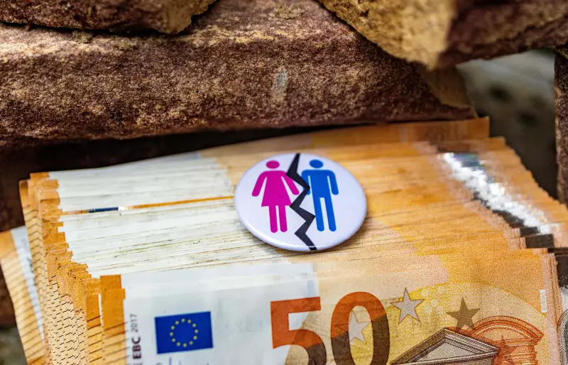 Mehrere 50€-Scheine liegen auf einem Haufen, darauf liegt ein Ansteck-Button, auf dem Piktogramme einer Frau und eines Mannes zu sehen sind, durch die Piktogramme geht eine gezackte schwarze Linie