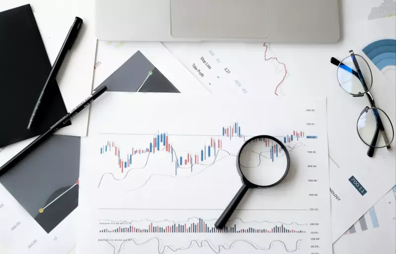 Ein Blatt papier, auf dem mehrere Graphen zu sehen sind. Darauf liegt eine Lupe, an der Seite liegt eine Brille