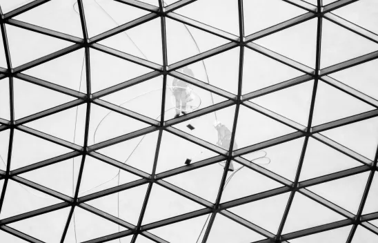 Zwei Arbeiter*innen beim Reinigen einer Glasfassade Zwei Arbeiter*innen beim Reinigen einer Glasfassade