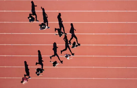 Eine Gruppe Läufer*innen auf einer Laufbahn. Eine Gruppe Läufer*innen auf einer Laufbahn.