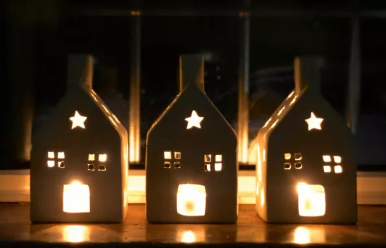 Drei Windlichter in Form von Häusern werden von Kerzen beleuchtet. Drei Windlichter in Form von Häusern werden von Kerzen beleuchtet.