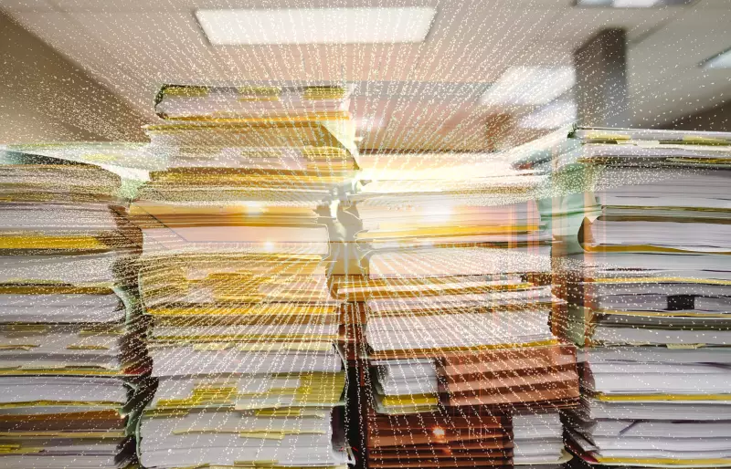 Aktenstapel hinter einem digitalen Lichstrahl.