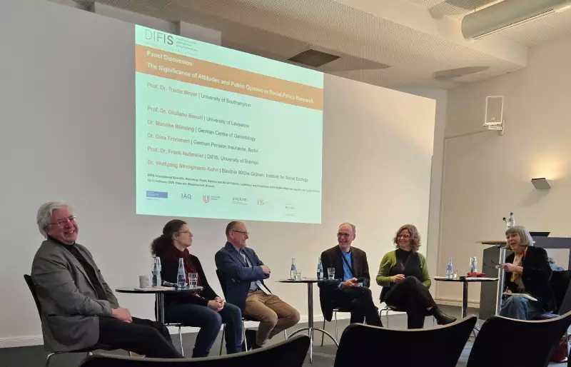 Mehrere Personen sitzen auf einem Podium, im Hintergrund läuft eine Präsentation