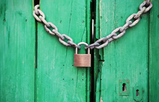 Metallenes Vorhängeschloss an einer Kette zum Verschluss einer mintgrünen Holztür Metallenes Vorhängeschloss an einer Kette zum Verschluss einer mintgrünen Holztür