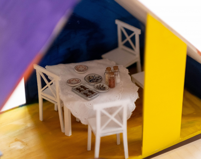 Ein Esstisch in einem Puppenhaus ist gedeckt.