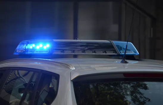 Der Ausschnitt eines Polizeiautos, auf dessen Dach Blaulicht leuchtet. Der Ausschnitt eines Polizeiautos, auf dessen Dach Blaulicht leuchtet.