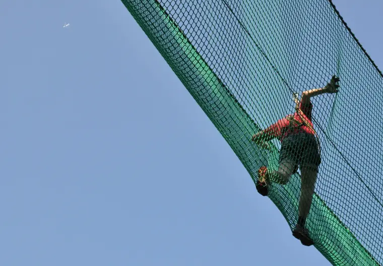 Eine Person überquert eine Netzbrücke, von unten fotografiert.