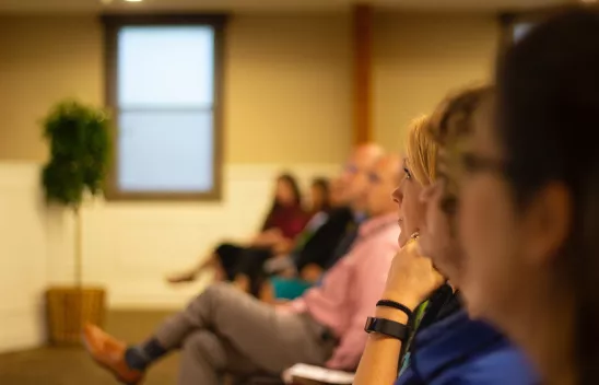 Mehrere Personen, die in einem Raum sitzen und einem Vortrag folgen