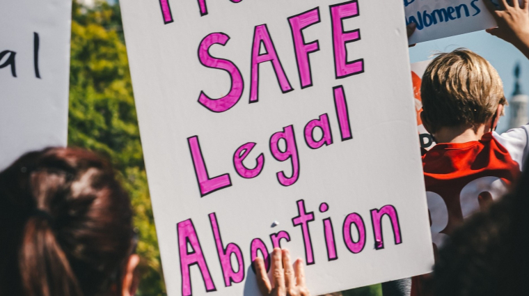Eine Person hält ein Schild auf einer Demonstration mit der Aufschrift: "Protect safe legal abortion", zu Deutsch "Schützt sicheren und legalen Schwangerschaftsabbruch"